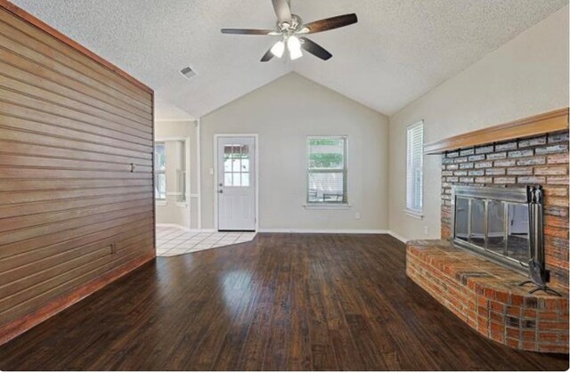 unfurnished living room with a fireplace, a textured ceiling, wood-type flooring, lofted ceiling, and ceiling fan