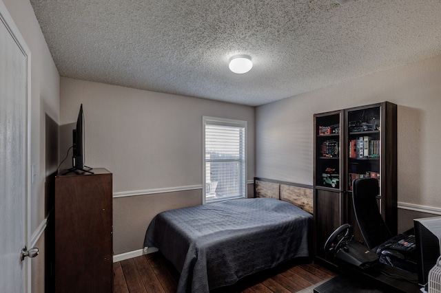 bedroom featuring a textured ceiling and dark hardwood / wood-style flooring