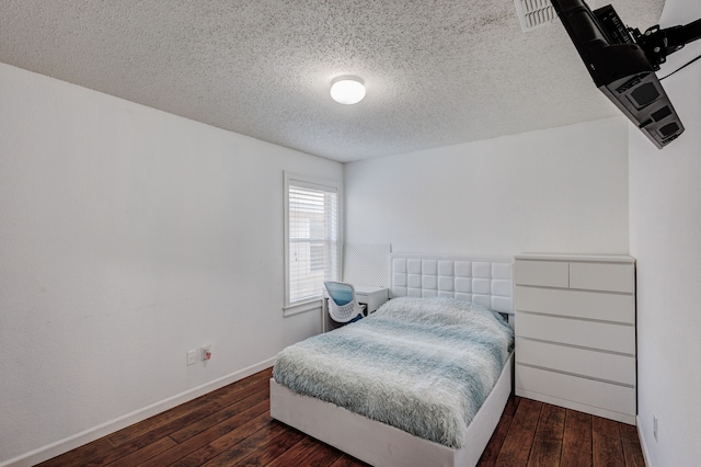 bedroom featuring a textured ceiling and dark hardwood / wood-style flooring