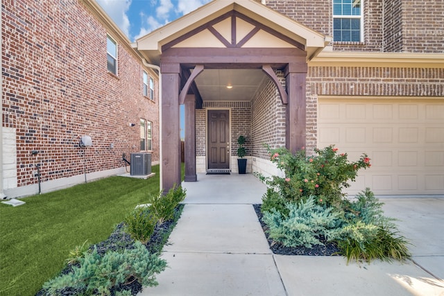 entrance to property featuring a garage, a yard, and central AC