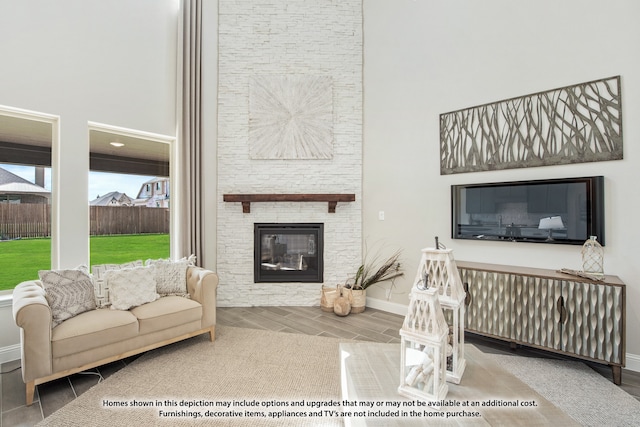 living room with a high ceiling, hardwood / wood-style floors, and a stone fireplace