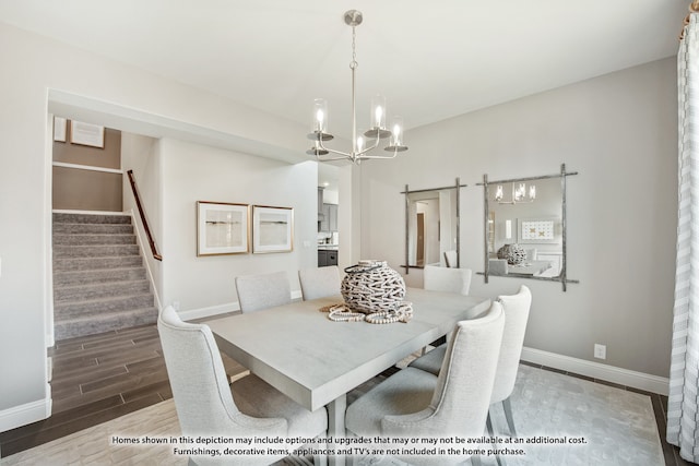 dining room featuring a barn door, wood-type flooring, and an inviting chandelier