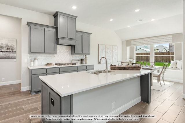 kitchen featuring gray cabinets, a kitchen island with sink, and sink