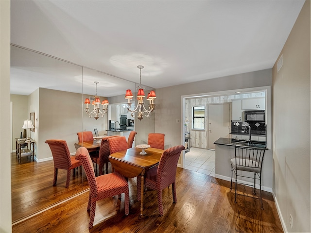 dining space with sink, a chandelier, and hardwood / wood-style floors