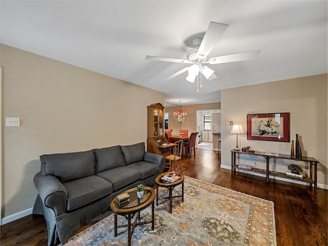 living room with ceiling fan with notable chandelier and dark hardwood / wood-style floors