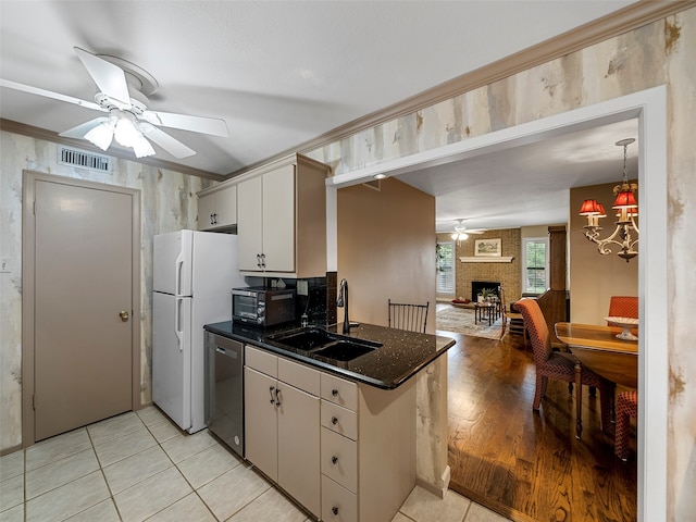 kitchen featuring white cabinetry, a fireplace, light hardwood / wood-style flooring, stainless steel dishwasher, and sink