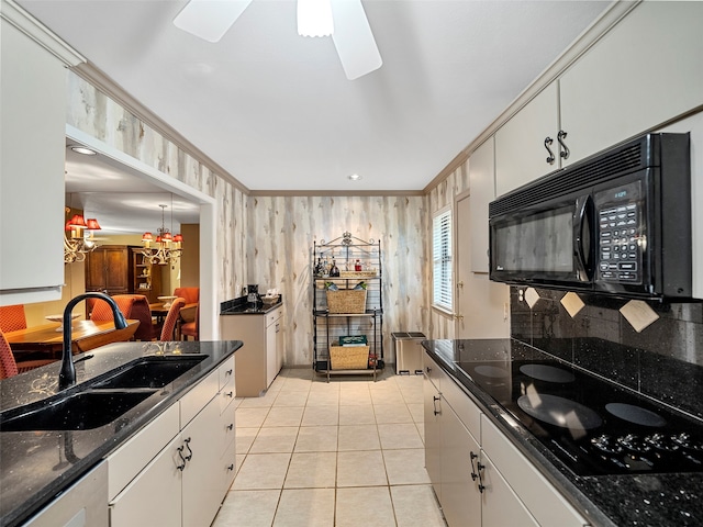 kitchen with sink, wood walls, white cabinetry, black appliances, and crown molding