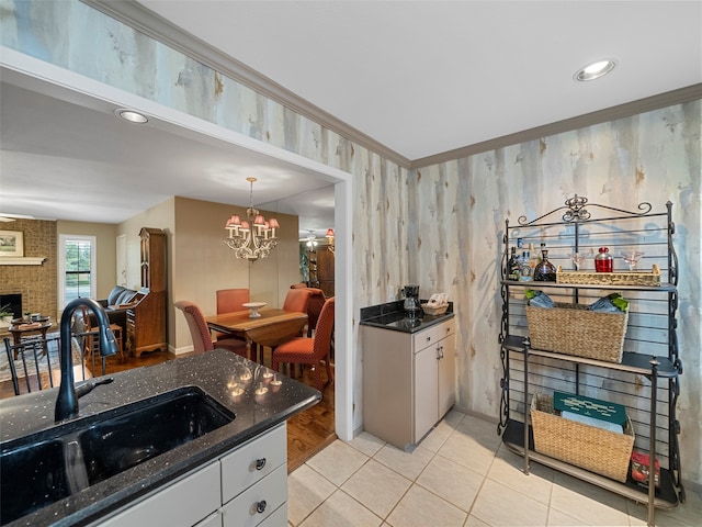 kitchen featuring pendant lighting, a chandelier, light tile patterned flooring, sink, and a brick fireplace