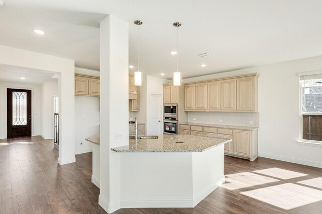 kitchen with light stone counters, stainless steel appliances, sink, light brown cabinets, and light hardwood / wood-style floors