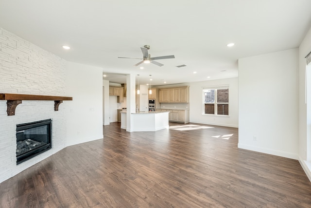 unfurnished living room with ceiling fan, dark hardwood / wood-style flooring, and a fireplace