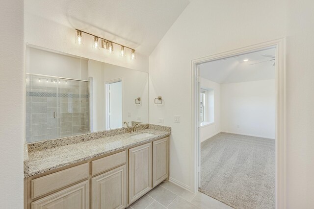 bathroom featuring tile patterned flooring, vanity, a shower with shower door, and vaulted ceiling