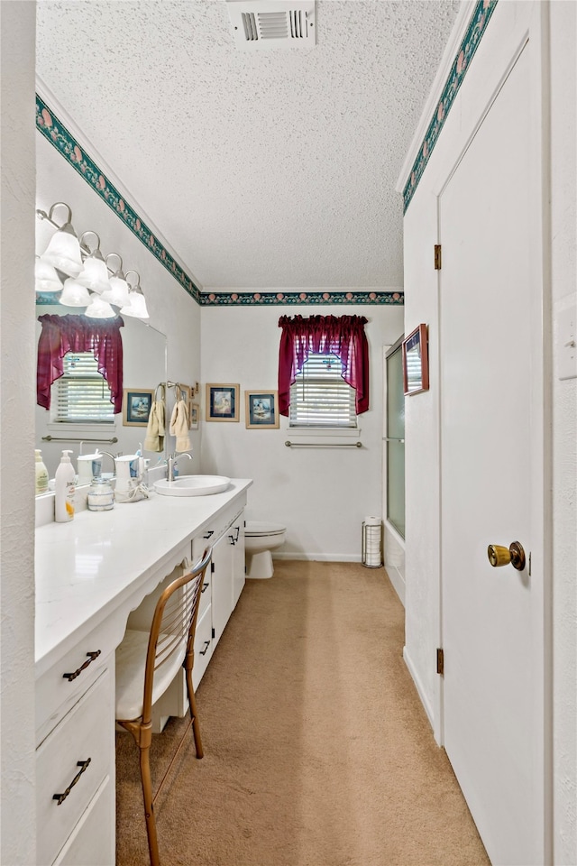 bathroom with a textured ceiling, a shower with door, vanity, and toilet