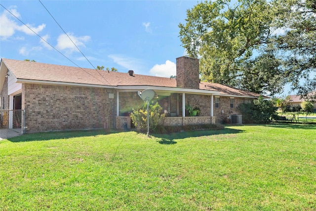 back of property with central AC unit and a lawn