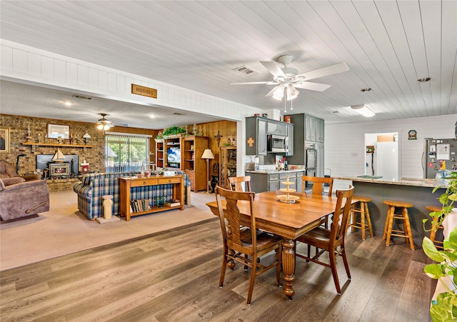 dining room featuring wood ceiling, wood walls, hardwood / wood-style floors, and ceiling fan