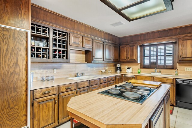 kitchen with black dishwasher, a center island, sink, stainless steel gas cooktop, and light tile patterned floors