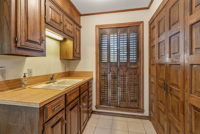 kitchen with light tile patterned flooring, ornamental molding, and sink