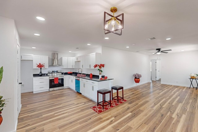 kitchen with wall chimney exhaust hood, light hardwood / wood-style floors, pendant lighting, appliances with stainless steel finishes, and white cabinetry