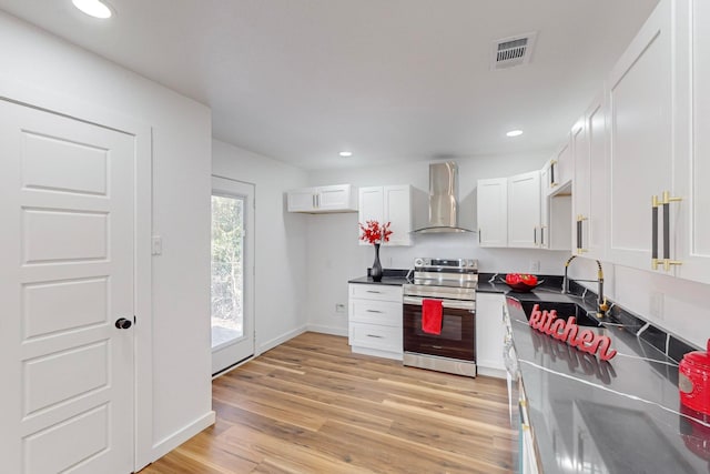 kitchen with wall chimney exhaust hood, light wood-type flooring, sink, stainless steel range with electric stovetop, and white cabinets