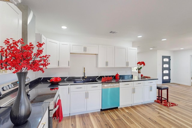 kitchen with stainless steel appliances, sink, white cabinetry, and light hardwood / wood-style flooring