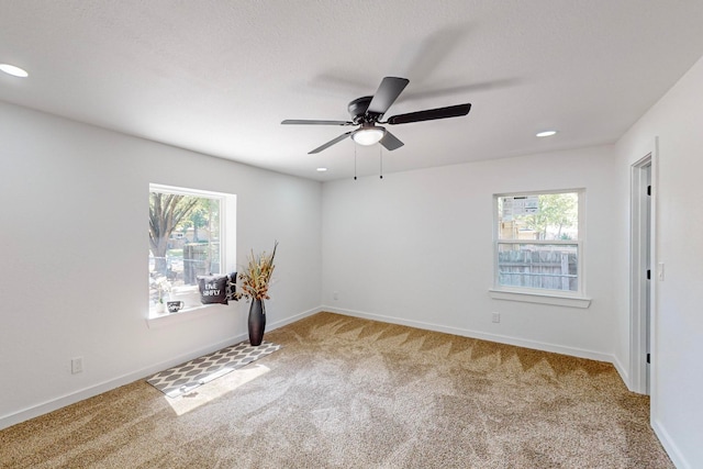 carpeted spare room with ceiling fan and a wealth of natural light