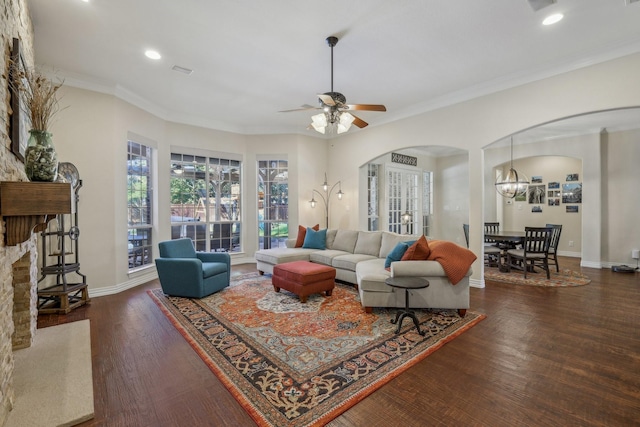 living room with crown molding, ceiling fan with notable chandelier, and dark hardwood / wood-style floors