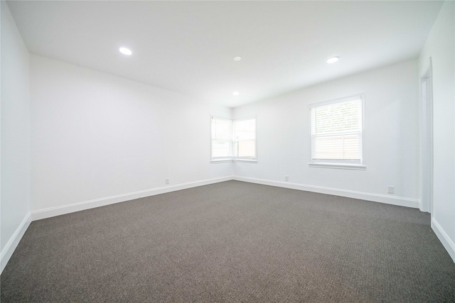 unfurnished room featuring dark colored carpet