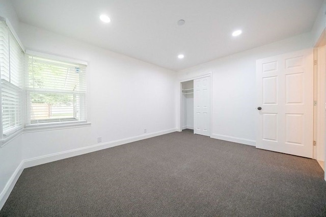 unfurnished bedroom featuring dark colored carpet and a closet