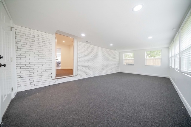 empty room with brick wall and dark colored carpet