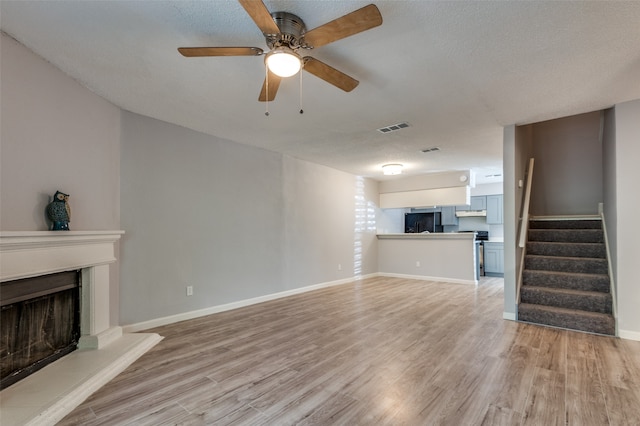 unfurnished living room with light wood-type flooring, ceiling fan, and a textured ceiling