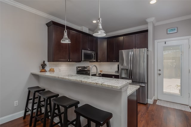 kitchen featuring hanging light fixtures, stainless steel appliances, light stone counters, dark hardwood / wood-style floors, and kitchen peninsula