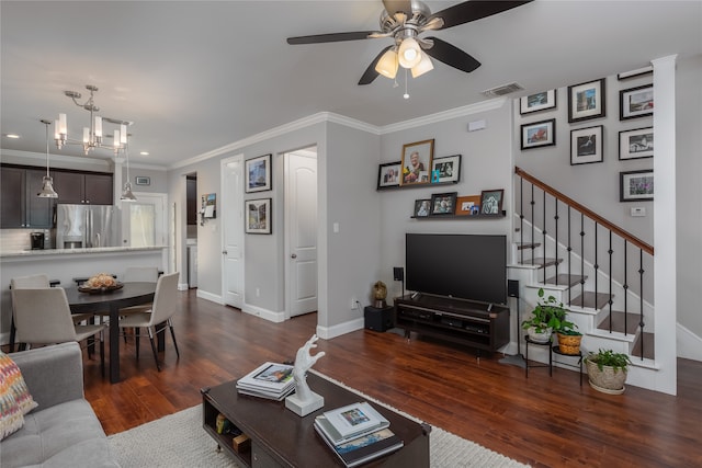 living room with dark wood-type flooring, ceiling fan with notable chandelier, and ornamental molding