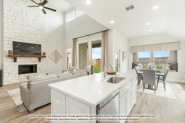 kitchen with a healthy amount of sunlight, white cabinets, a kitchen island with sink, and sink