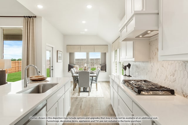 kitchen with white cabinetry, backsplash, light hardwood / wood-style flooring, stainless steel gas stovetop, and sink