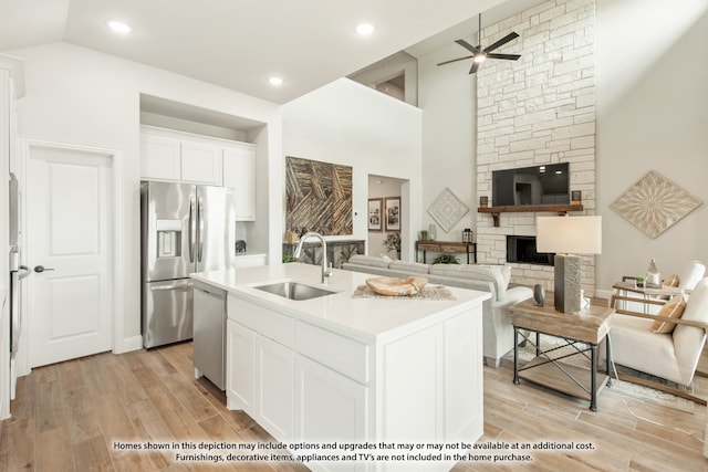 kitchen with sink, white cabinetry, a fireplace, a center island with sink, and appliances with stainless steel finishes