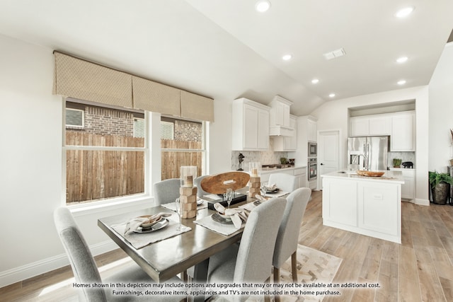 dining space featuring light wood-type flooring, lofted ceiling, and sink