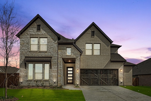 view of front facade with driveway, stone siding, an attached garage, a yard, and brick siding