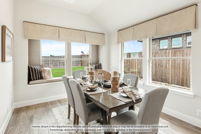 dining area with vaulted ceiling, plenty of natural light, and hardwood / wood-style floors