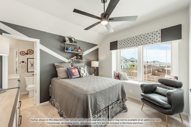 bedroom featuring ceiling fan, ensuite bath, vaulted ceiling, and light carpet