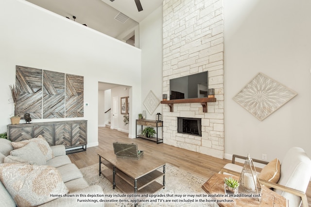 living room with high vaulted ceiling, ceiling fan, light hardwood / wood-style flooring, and a fireplace