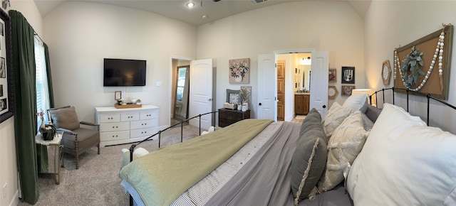 bedroom featuring ensuite bath, multiple windows, light colored carpet, and lofted ceiling