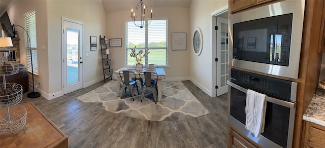 dining area with vaulted ceiling, dark hardwood / wood-style floors, and an inviting chandelier