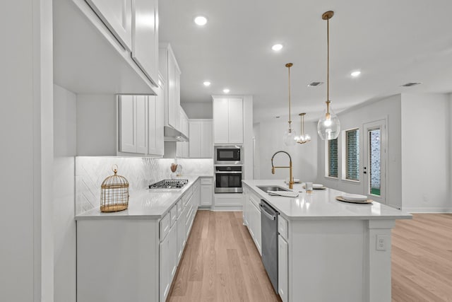 kitchen with sink, white cabinetry, decorative light fixtures, a center island with sink, and appliances with stainless steel finishes