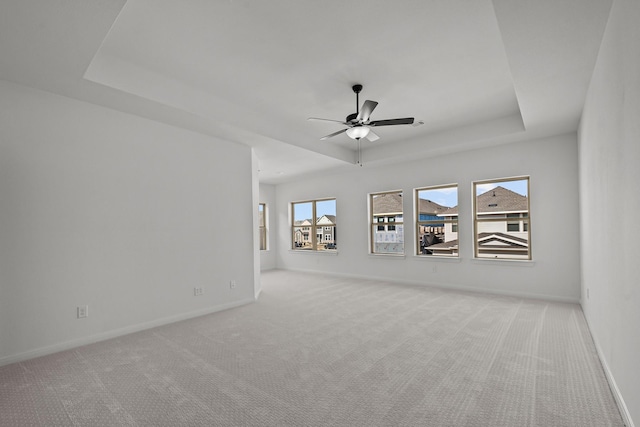 carpeted spare room with ceiling fan and a raised ceiling