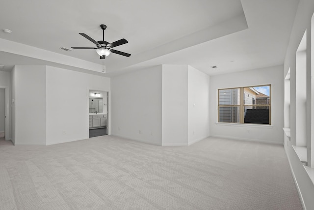 spare room featuring ceiling fan, a tray ceiling, and light carpet