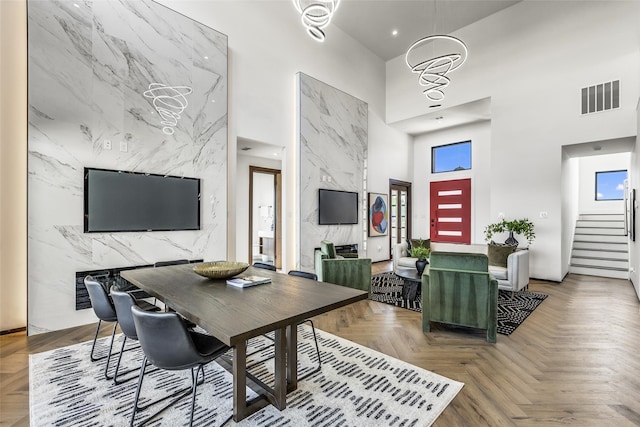 dining room with parquet floors, tile walls, a high ceiling, and a wealth of natural light