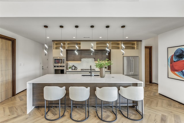 kitchen with a center island with sink, appliances with stainless steel finishes, light parquet floors, and pendant lighting