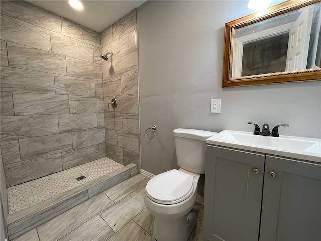 bathroom featuring vanity, toilet, and tiled shower