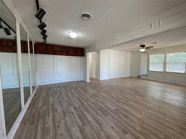 interior space with a textured ceiling, ceiling fan, and light hardwood / wood-style flooring