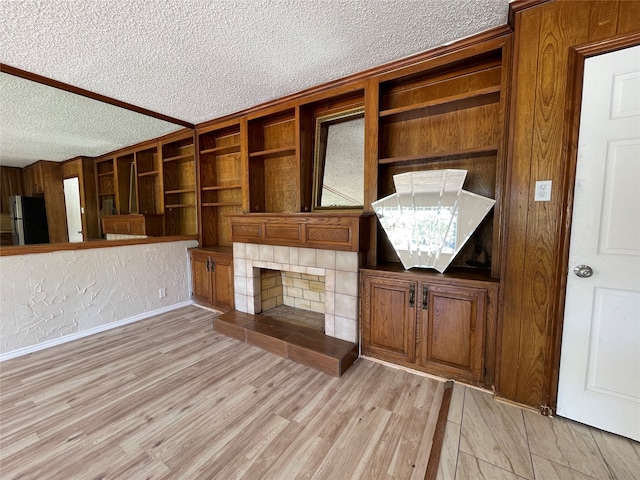 unfurnished living room featuring a textured ceiling, a tiled fireplace, and light hardwood / wood-style floors