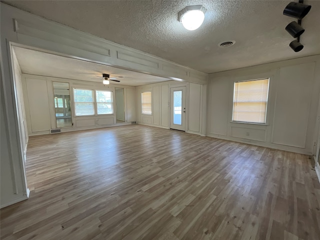 spare room with light wood-type flooring, a textured ceiling, and ceiling fan